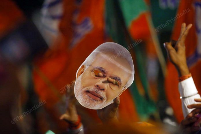 A supporter holds Modi's mask | Photo: Praveen Jain | ThePrint