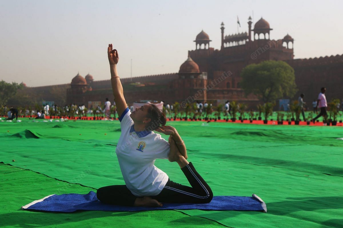 A participant performs yoga, with the Red Fort in the backdrop | Photo: Manisha Mondal | ThePrint