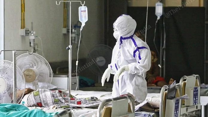 A healthcare worker attending to a Covid patient in PPE | Praveen Jain | ThePrint