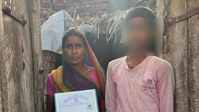 Sarvila Devi of Thalpos village in Nawada holds up the Class 10 certificate of her elder son Gulshan, who is now in jail. Her younger son stands with her | Jyoti Yadav | ThePrint