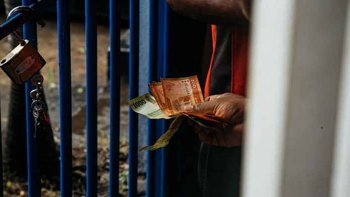 A resident holds Sri Lankan rupee notes in Colombo | Photo via Bloomberg