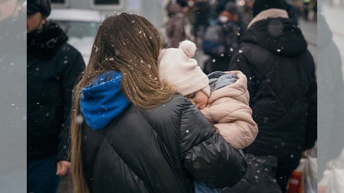 A displaced Ukrainian carries her child after crossing the border in Siret, Romania, on 2 March 2022 | Representational image | Bloomberg