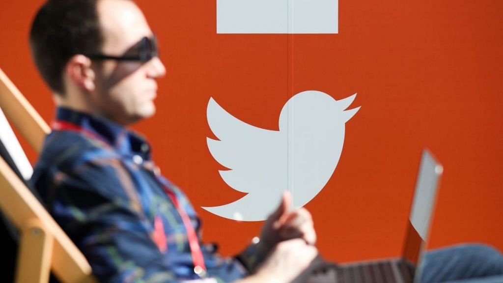 The Twitter Inc. logo sits on a wall as a man sits on a deckchair in Barcelona | Representational image | Bloomberg