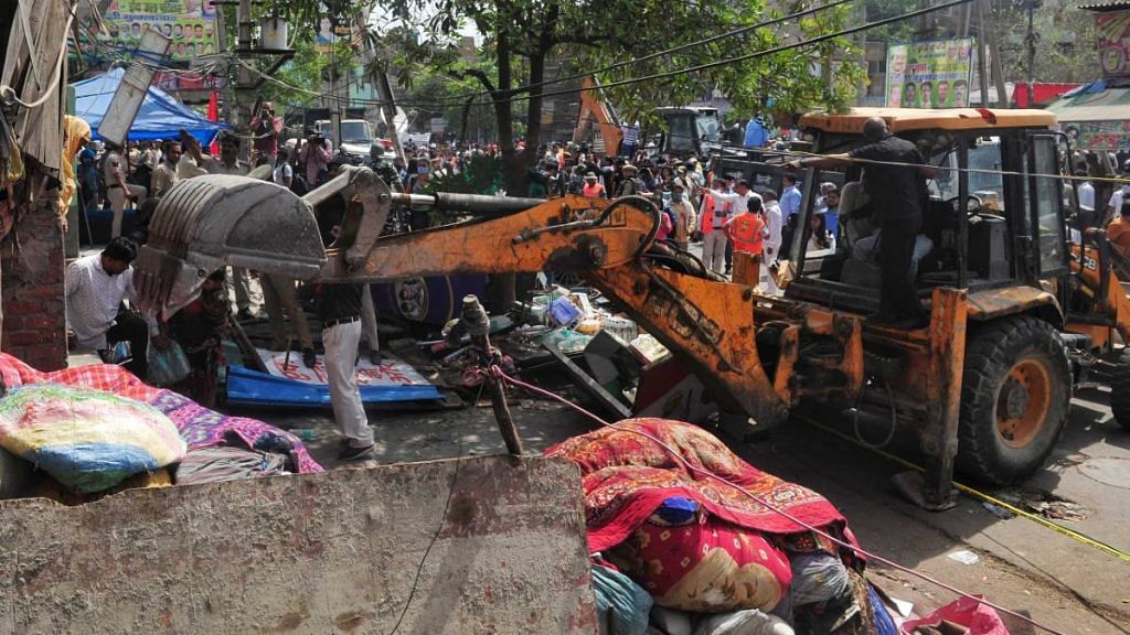 A bulldozer razes structures in the area that saw communal violence during a Hindu religious procession on Saturday at Jahangirpuri, New Delhi | Photo: Suraj Singh Bisht | ThePrint