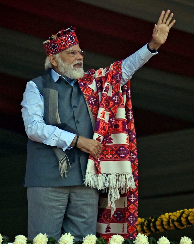 Prime Minister Narender Modi wearing a traditional Pahart cap and woolen shawl waves to supporters at a public meeting, in Mandi. 27 Dec 2021