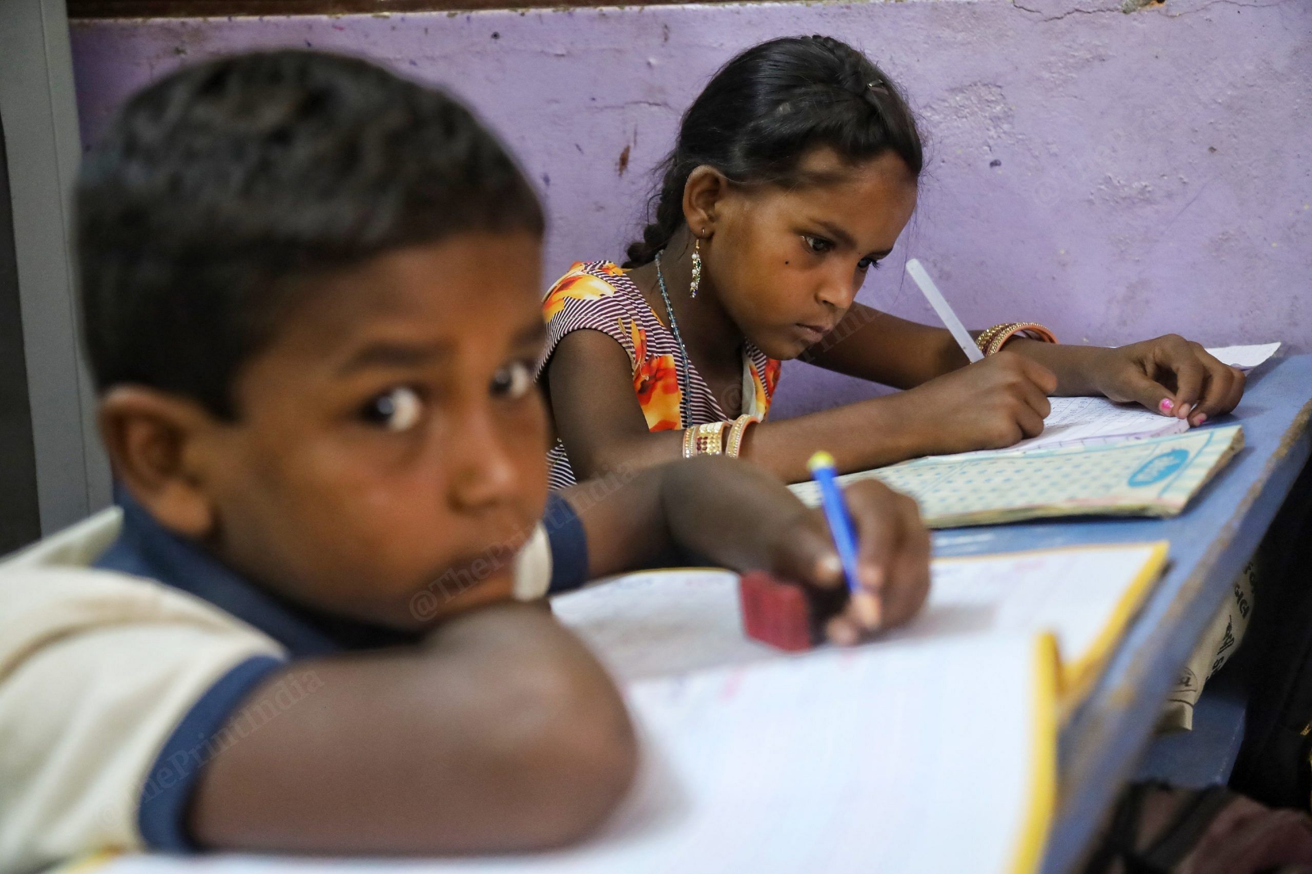 Two students at Shree Shakti Nagar school in Kachchh district work patiently, as their teacher (not in the photo), attends to other students | Photo: Manisha Mondal | ThePrint