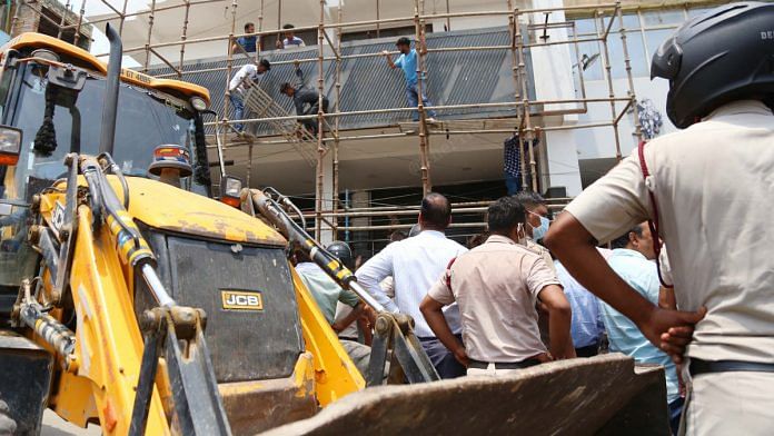 Shaheen Bagh residents take down scaffolding while a 'JCB' waits Monday | Photo: Manisha Mondal | ThePrint