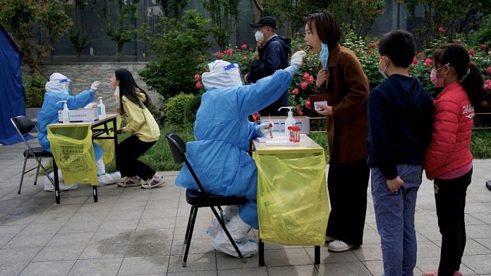A health worker takes a swab sample from a woman to conduct Covid test in Beijing on 9 May 2022 | Photo: Noel Celis/AFP/Getty Images via Bloomberg
