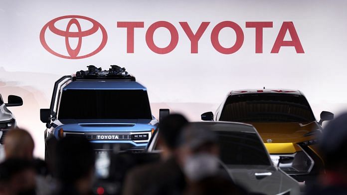 The Toyota Motor logo behind the company's prototype of electric vehicles on display at the company's showroom in Tokyo, Japan | Photo: Kiyoshi Ota | Bloomberg