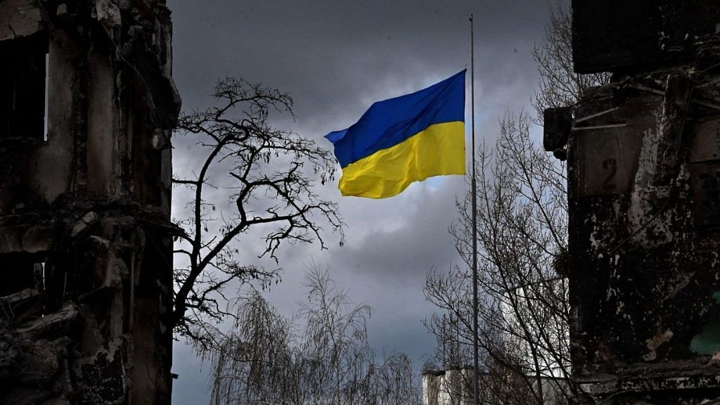 The Ukrainian flag flutters between buildings destroyed in bombardment, in the Ukrainian town of Borodianka, in the Kyiv region | Photographer: Sergei Supinsky/AFP/Getty Images via Bloomberg
