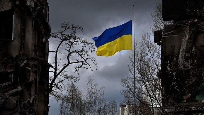 The Ukrainian flag flutters between buildings destroyed in bombardment, in the Ukrainian town of Borodianka, in the Kyiv region | Photographer: Sergei Supinsky/AFP/Getty Images via Bloomberg