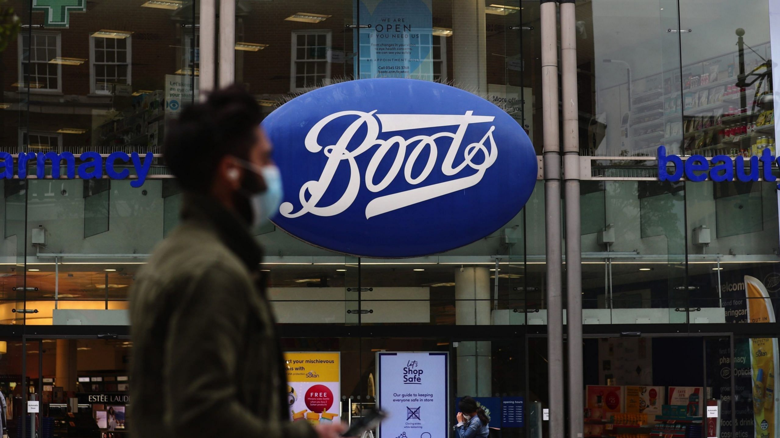 A pedestrian wearing a protective face mask passes a Boots pharmacists on Oxford Street in London | Photo: Simon Dawson | Bloomberg