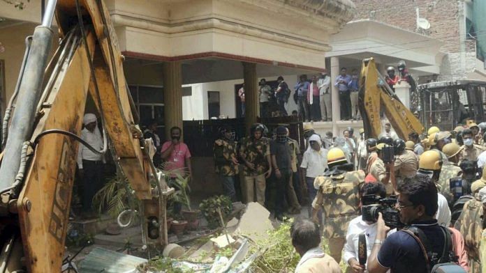 Security personnel and locals gather as a bulldozer demolished the residence of Javed Ahmed in Prayagraj on Sunday | PTI