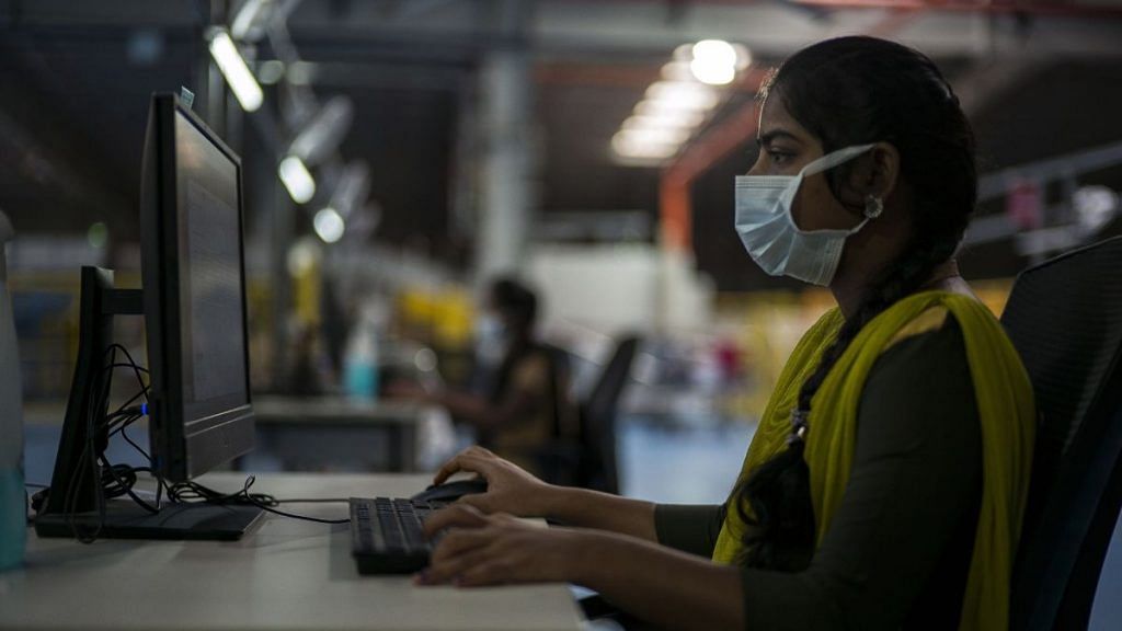 A worker wearing a protective mask works on a computer at a Flipkart warehouse in Koduvalli, Thiruvallur | Representational image | Bloomberg
