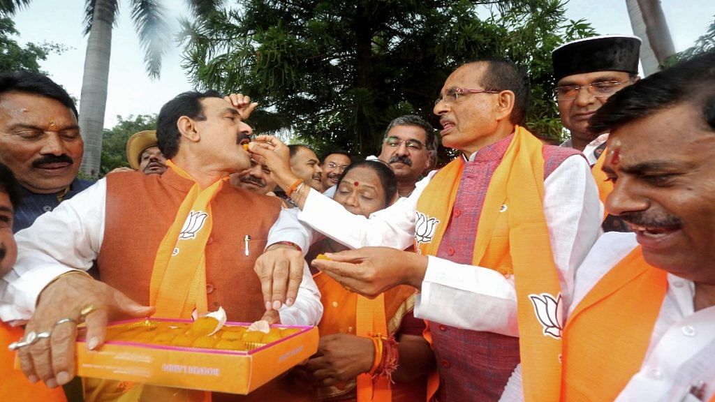 Madhya Pradesh Chief Minister Shivraj Singh Chouhan offers sweets to state Home Minister Narottam Mishra as they celebrate the party's victory in local body elections, at the BJP state headquarters in Bhopal Sunday | ANI