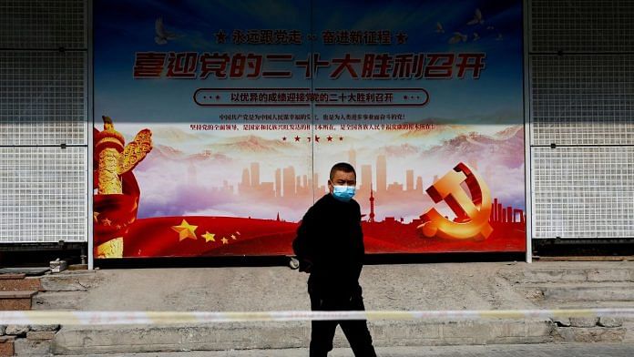 A man walks past a poster welcoming the 20th National Congress of the Communist Party of China, in Beijing, China 14 October 2022 | Reuters/Tingshu Wang