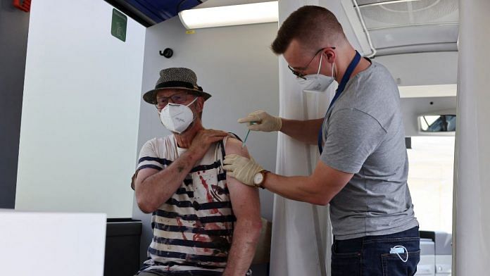 A man receives a dose of the vaccine against Covid-19 in a bus, after floods caused by heavy rainfalls, in Germany | Reuters