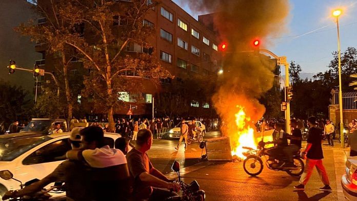 A police motorcycle burns during a protest over the death of Mahsa Amini, a woman who died after being arrested by the Islamic republic's 'morality police', in Tehran, Iran | WANA (West Asia News Agency) via Reuters