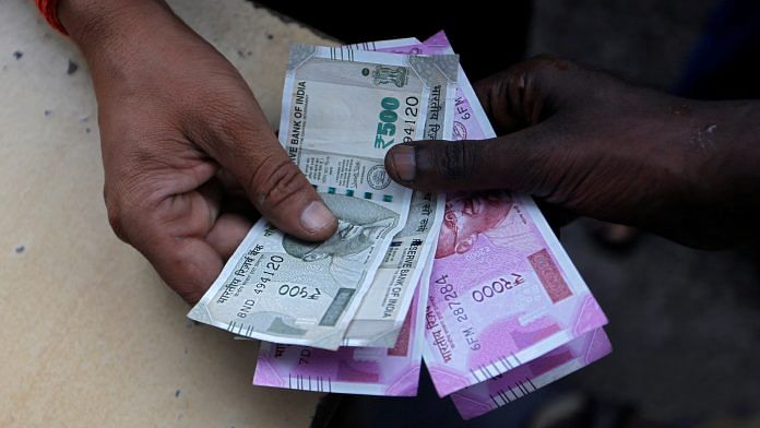 A customer hands Indian currency notes to an attendant at a fuel station in Mumbai | REUTERS File