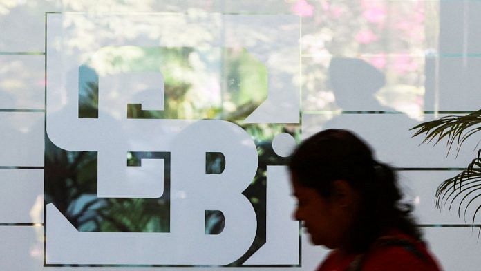 A woman walks past the logo of the Securities and Exchange Board of India (SEBI), at its headquarters in Mumbai, India | Reuters