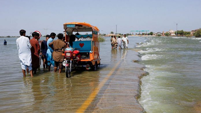 File photo of displaced people standing on flooded highway, following rains and floods during the monsoon season in Sehwan, Pakistan, 16 September, 2022 | Reuters