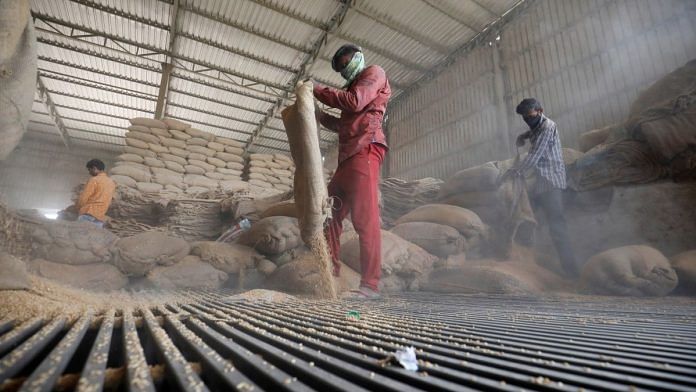 File photo of workers emptying wheat sacks for sifting at a grain mill on the outskirts of Ahmedabad | Reuters