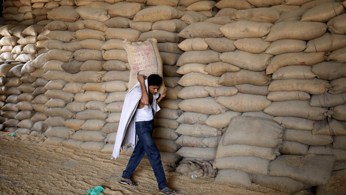 A worker carries a sack of wheat for sifting at a grain mill on the outskirts of Ahmedabad, India,16 May 2022. Reuters/Amit Dave