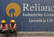 Labourers rest in front of an advertisement for Reliance Industries | Image ia Reuters/ Shailesh Andrade