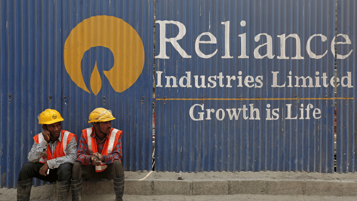 Labourers rest in front of an advertisement for Reliance Industries | Image ia Reuters/ Shailesh Andrade