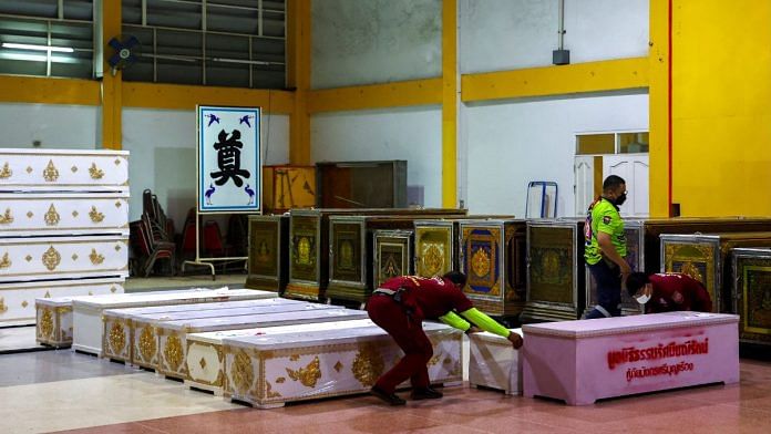 Rescue workers arrange coffins containing the body of victims that were killed in a mass shooting in the town of Uthai Sawan in Thailand on 7 October 2022. | Reuters