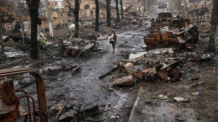 A woman walks amid destroyed Russian tanks in Bucha, Ukraine, 3 April 2022 | Flickr