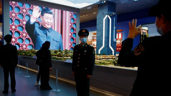 A member of the PLA poses for pictures in front of models of military equipment and a giant screen displaying Chinese President Xi Jinping in Beijing | Reuters file photo