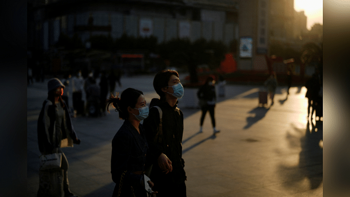 People wearing protective face masks walk, following the coronavirus disease (COVID-19) outbreak, in Shanghai, China, October 10, 2022. REUTERS/Aly Song