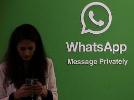 A woman uses her phone next to a logo of the WhatsApp application during Global Fintech Fest in Mumbai | Reuters file photo