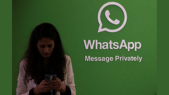 A woman uses her phone next to a logo of the WhatsApp application during Global Fintech Fest in Mumbai | Reuters file photo