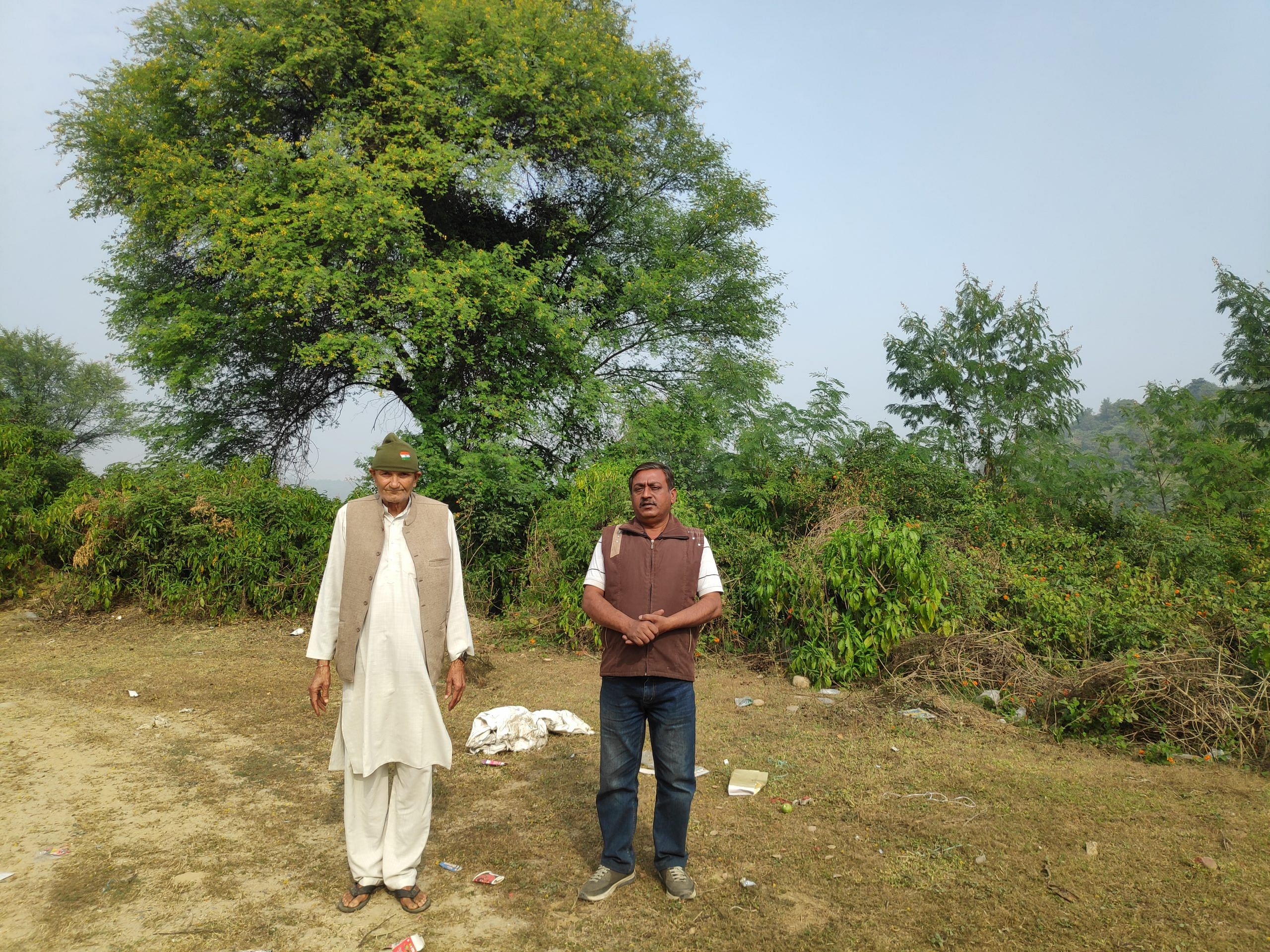 Petitioners Harish Kumar (in brown jacket) and Balbir Singh (in green cap) at the spot which they claim to be their land at the designated plot for the bulk drug park in Haroli tehsil, Una | Sonal Matharu, Theprint