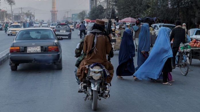 A group of women wearing burqas crosses the street as members of the Taliban drive past in Kabul, Afghanistan | Reuters file photo/Jorge Silva