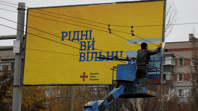 A municipality worker covers a pro-Russian billboard with a Ukrainian Armed Forces one reading: 