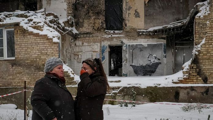 Local resident cries as she speaks with her neighbour near a work of graffiti artist Banksy at the wall of destroyed building in the Ukrainian village of Horenka, which was heavily damaged by fighting in the early days of the Russian invasion, 19 November, 2022 | Reuters