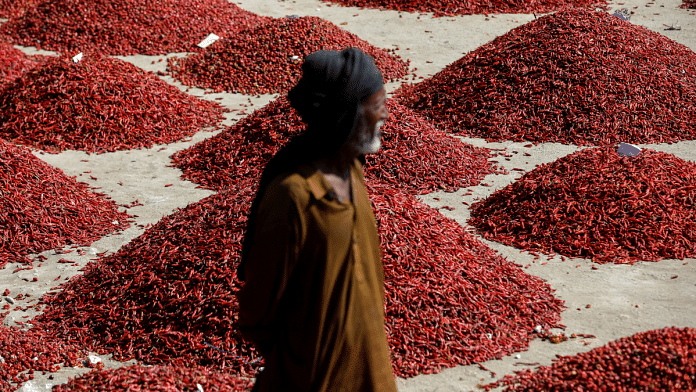 Man standing in front of mounds of red chili pepper at the wholesale market in Pakistan's Kunri | Akhtar Soomro | Reuters