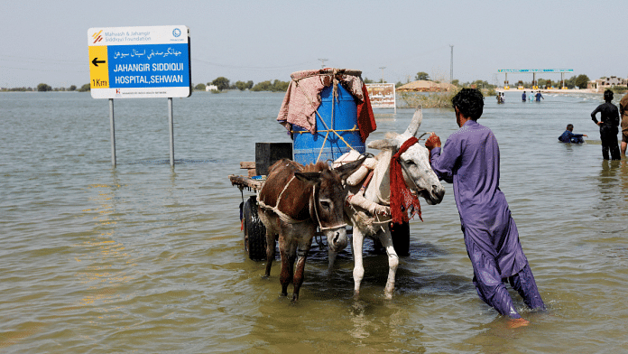 A flood victim pushes his donkey cart on flooded highway, following rains and floods during the monsoon season in Pakistan | Reuters File Photo/Akhtar Soomro