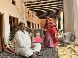 Vikrant Som's parents holding his framed photo in their verandah | Jyoti Yadav, ThePrint