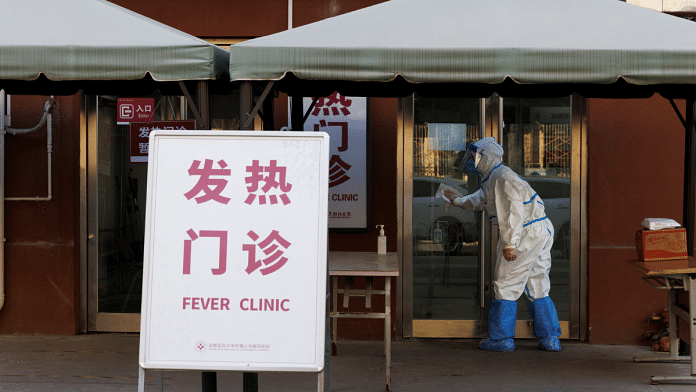 A health worker in a protective suit wipes the door to a fever clinic at a hospital as coronavirus disease outbreaks continue in Beijing | Reuters Photo/Thomas Peter