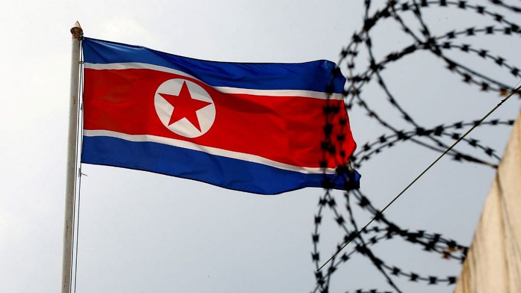 A North Korea flag flutters next to concertina wire | REUTERS/Edgar Su
