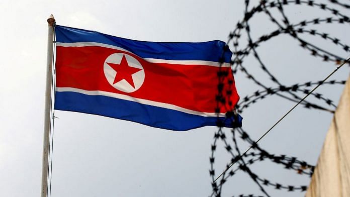 A North Korea flag flutters next to concertina wire | REUTERS/Edgar Su