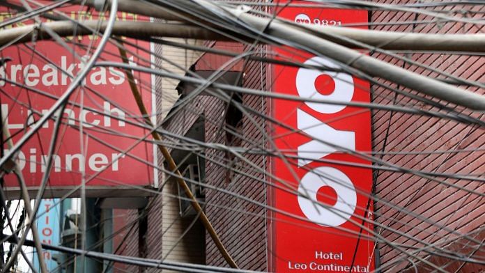 The logo of OYO installed on a hotel building is seen through wires in an alley in New Delhi | Reuters file photo