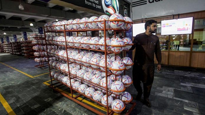 A worker moves finished balls out of the production area inside the soccer ball factory in Sialkot, Pakistan | Reuters