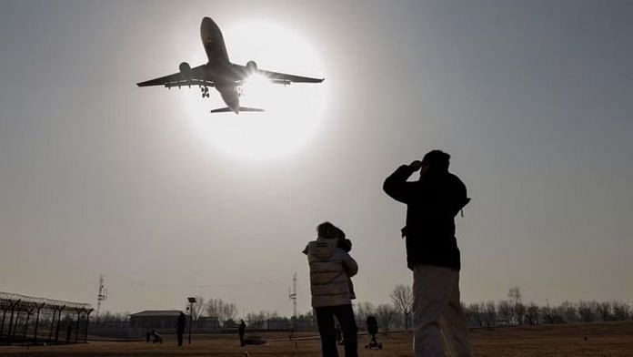 People watch a plane land at Beijing Capital International Airport as coronavirus disease (COVID-19) outbreaks continue in Beijing, China | REUTERS/Thomas Peter