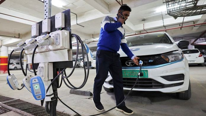 A man charges an electric vehicle (EV) at the charging hub of Indian ride-hailing BluSmart Electric Mobility in Gurugram, India, 9 December 2022 | Reuters/Anushree Fadnavis