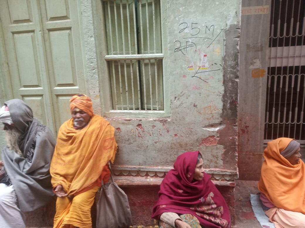 Sadhus and beggars sit outside a house that has been marked under the survey | Photo: Krishan Murari | The Print